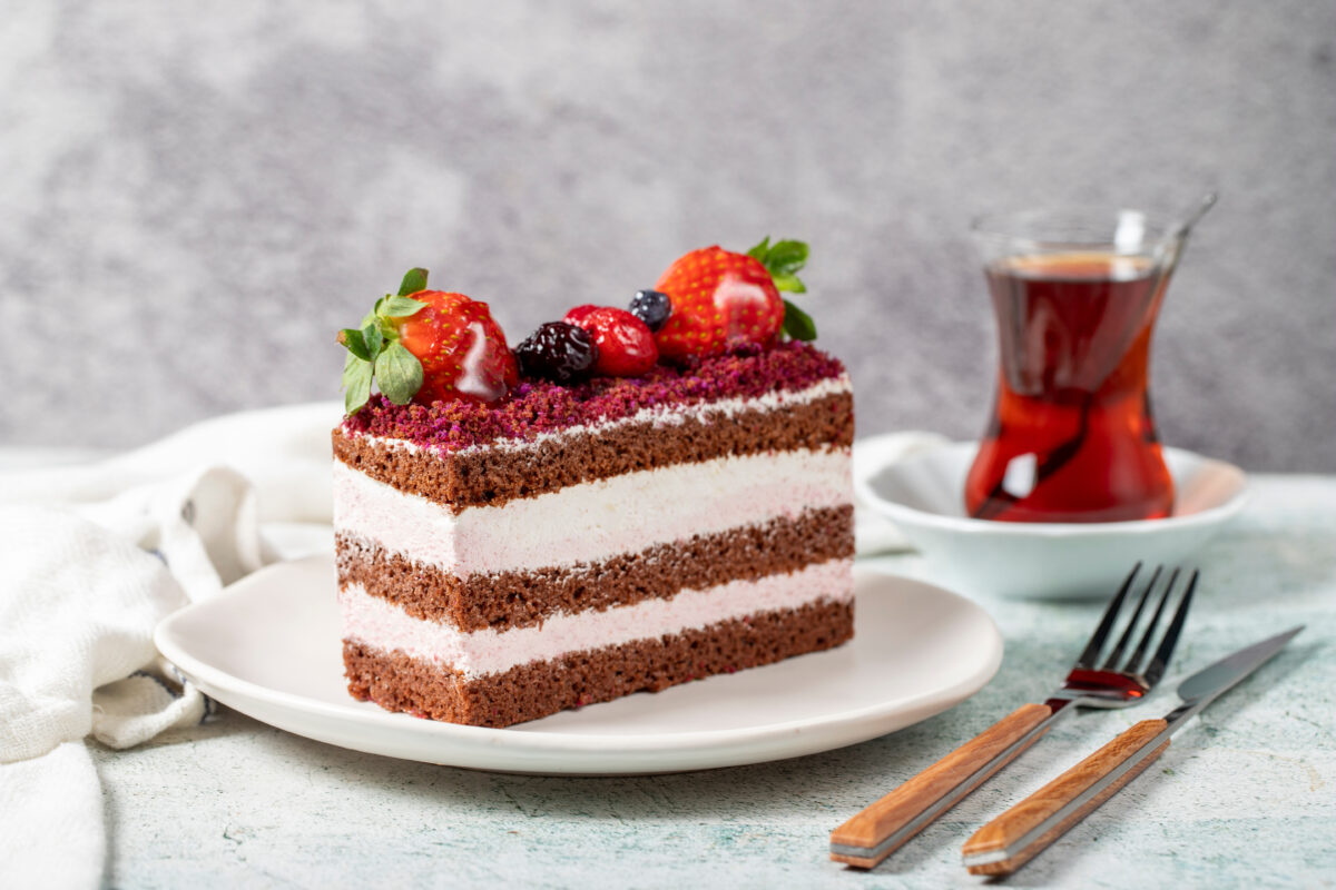 Fruit and whipped cream cake. Layered cake with forest fruit and cream on the plate. close up